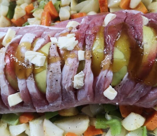 SUROWY SCHAB NACIĘTY I NADZIANY JABŁKAMI, POSMAROWANY MIODEM, UŁOŻONY NA WARZYWACH W NACZYNIU DO PIECZENIA